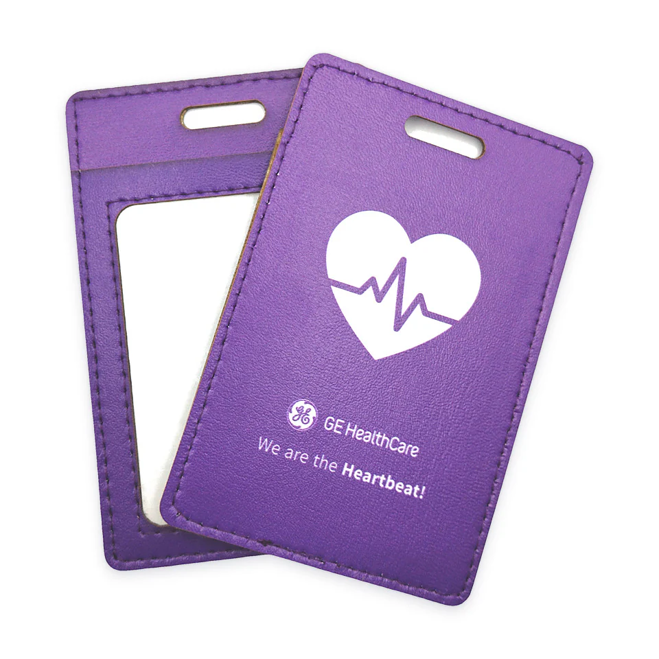 Portacredencial de simil-piel cosido en morado, muestra GE HealthCare: frente con ventana y reverso con logo